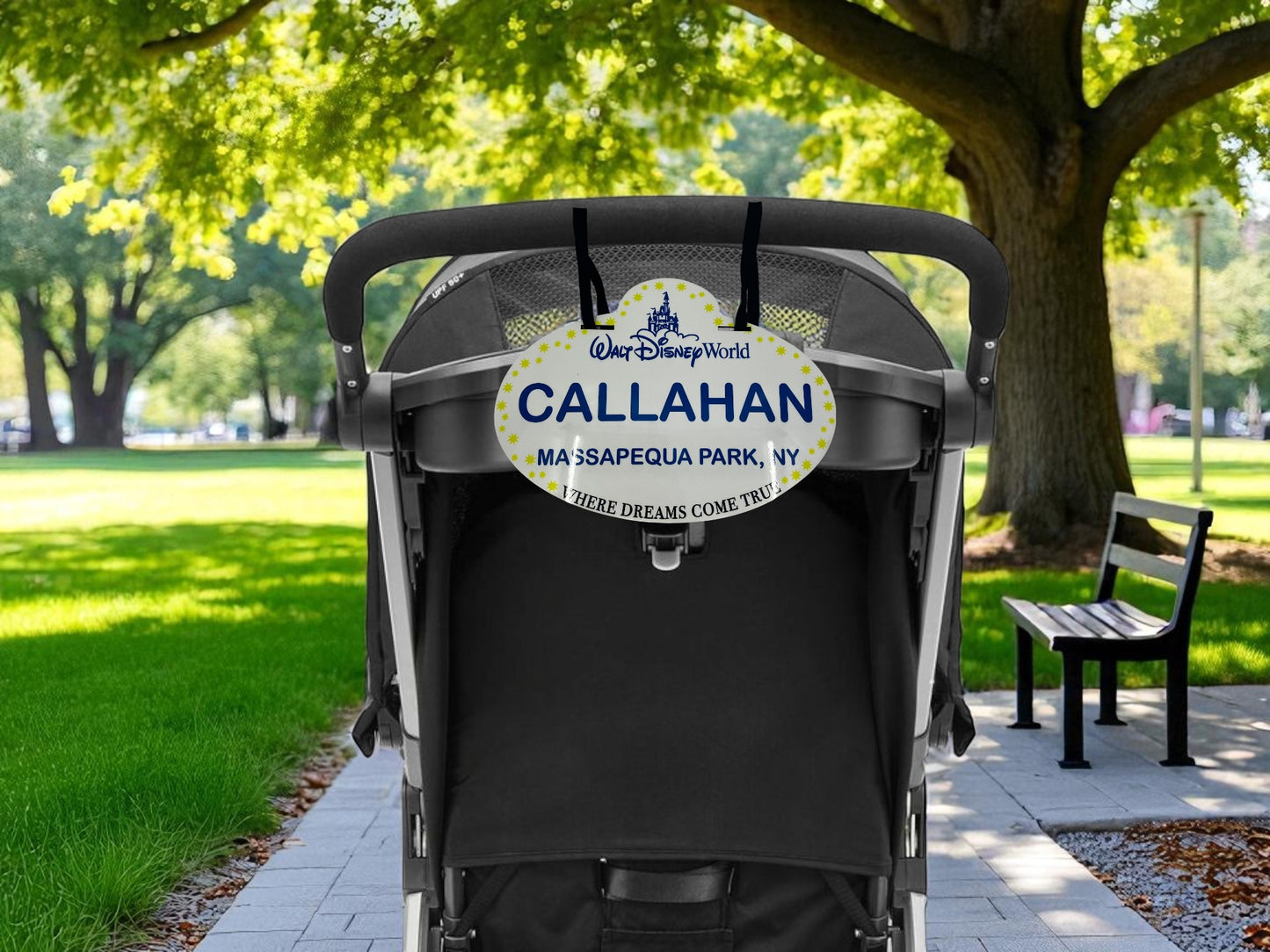 Black stroller with a personalized name tag in a park setting
