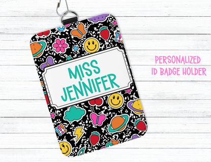 Personalized ID badge holder with colorful design and 'Miss Jennifer' text on a white wooden background